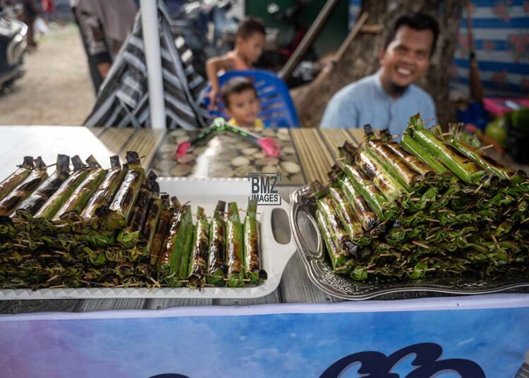 Pedagang makanan khas Lalampa menunggui pembeli di Pasar Ramadhan di Palu, Sulawesi Tengah, Selasa (12/3/2024). Lalampa adalah salah satu penganan khas yang banyak dijajakan pedagang di bulan Ramadhan di wilayah itu, terbuat dari beras ketan putih dicampur santan dan dibungkus daun pisang lalu dipanggang di atas bara api. bmzIMAGES/Basri Marzuki